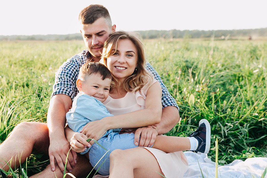 Personal Insurance - Family Hugging and Smiling in Green Grassy Field